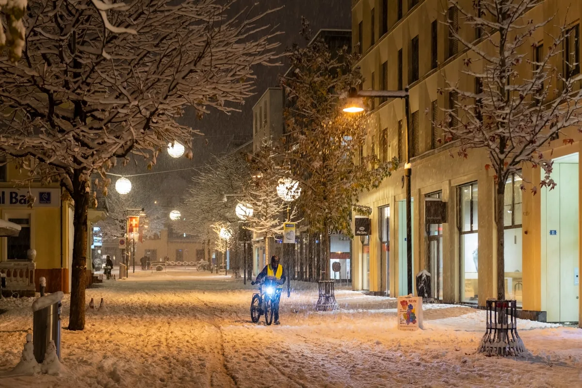 Ein Velo wird unter der Weihnachtsbeleuchtung durch die Postgasse geschoben. Da helfen auch Winterpneus nichts mehr. Die Weihnachtsbeleuchtung in Uster erhellt wieder die Winternächte.